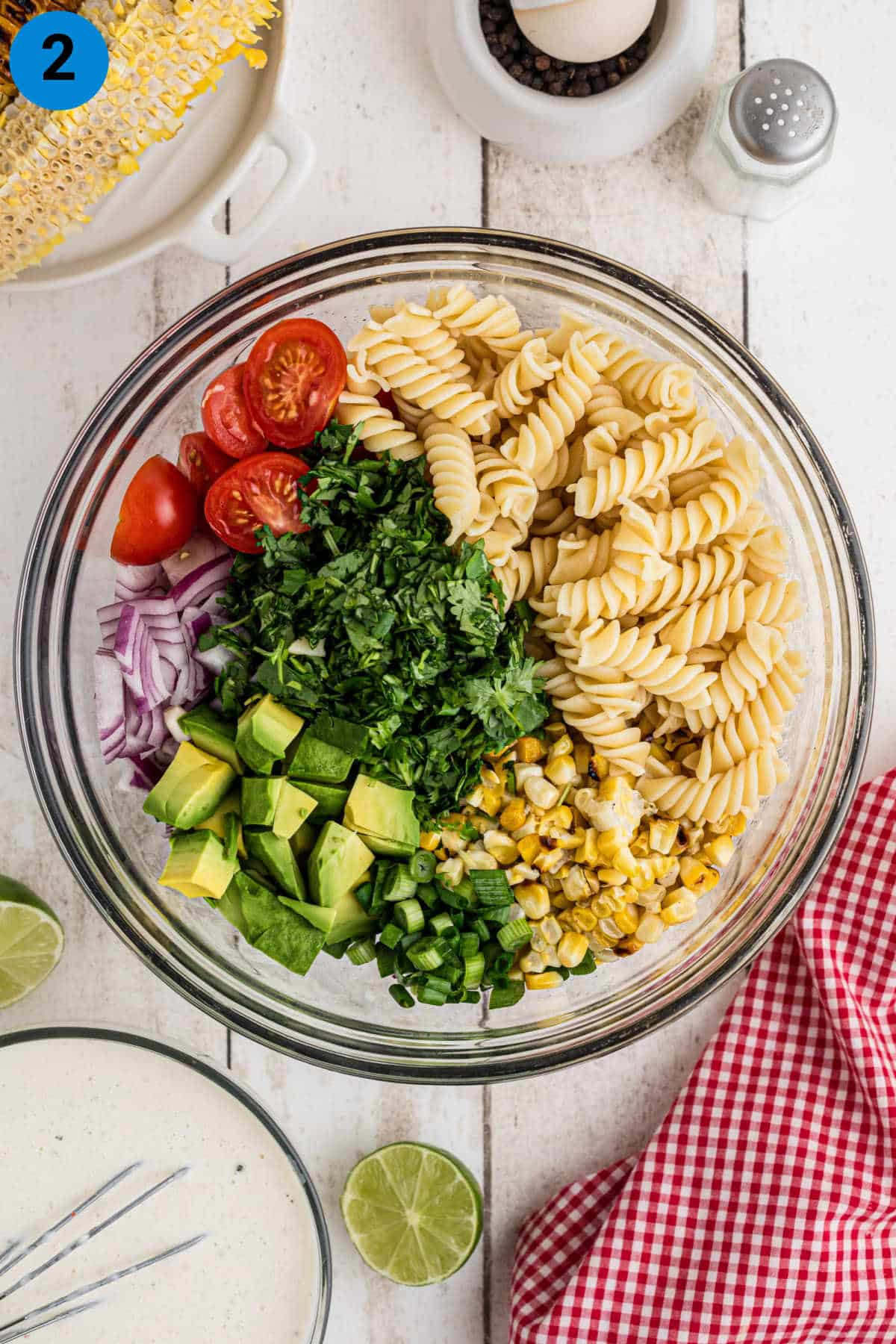 A large salad bowl with the ingredients needed arranged, to show what's needed for this pasta salad recipe.
