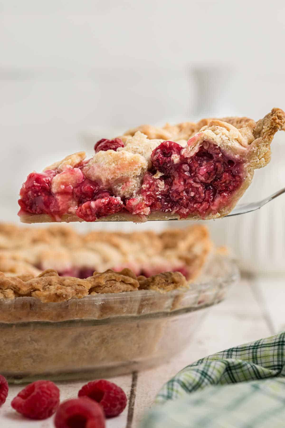 A slice of raspberry pie being lifted out of a pie dish.