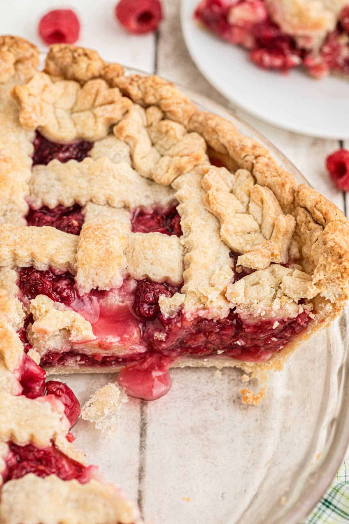 Overhead close up of a raspberry pie, with a slice removed so you can see the delicious inside.