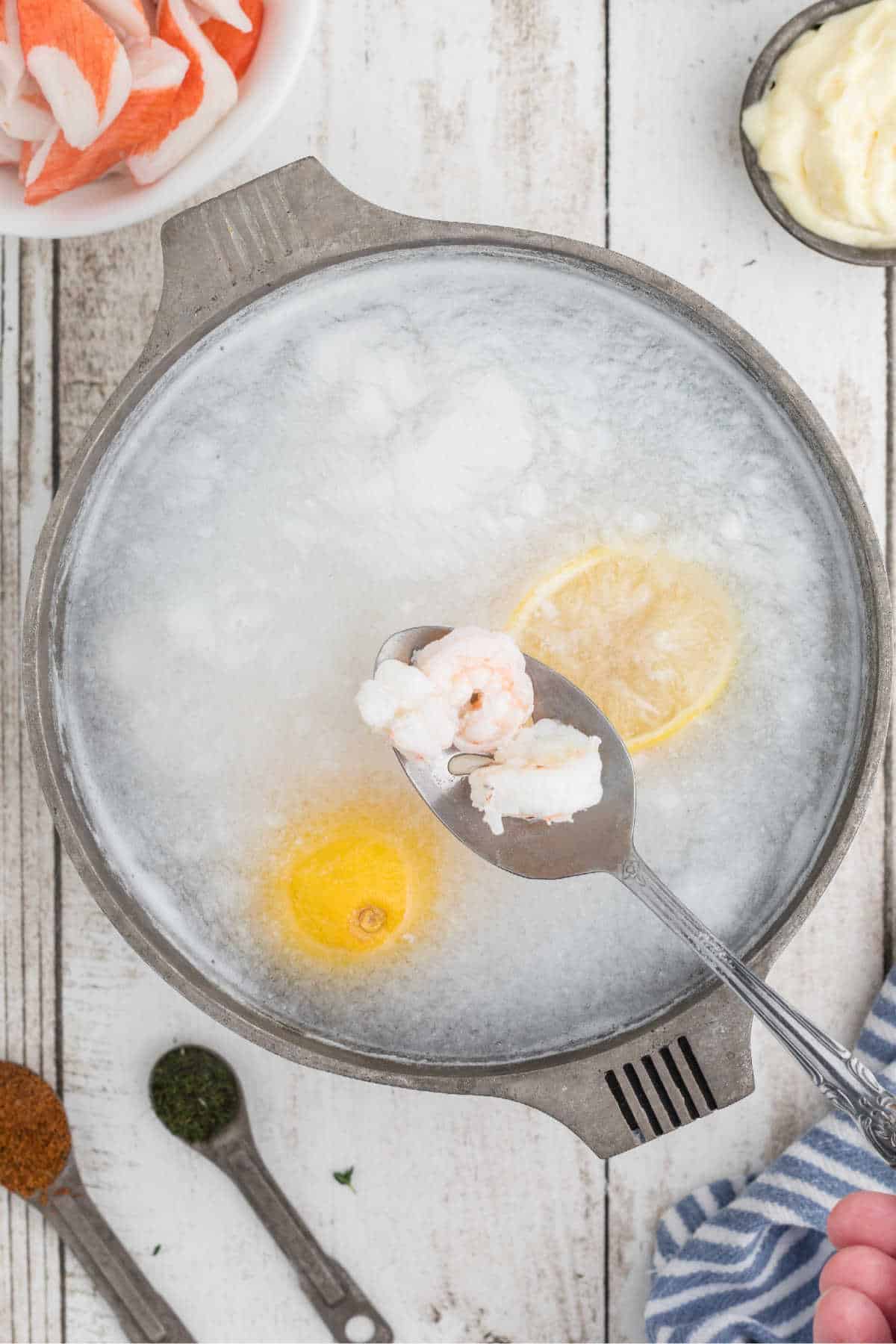 A small pot with lemons and dropping shrimp into the boiling water.
