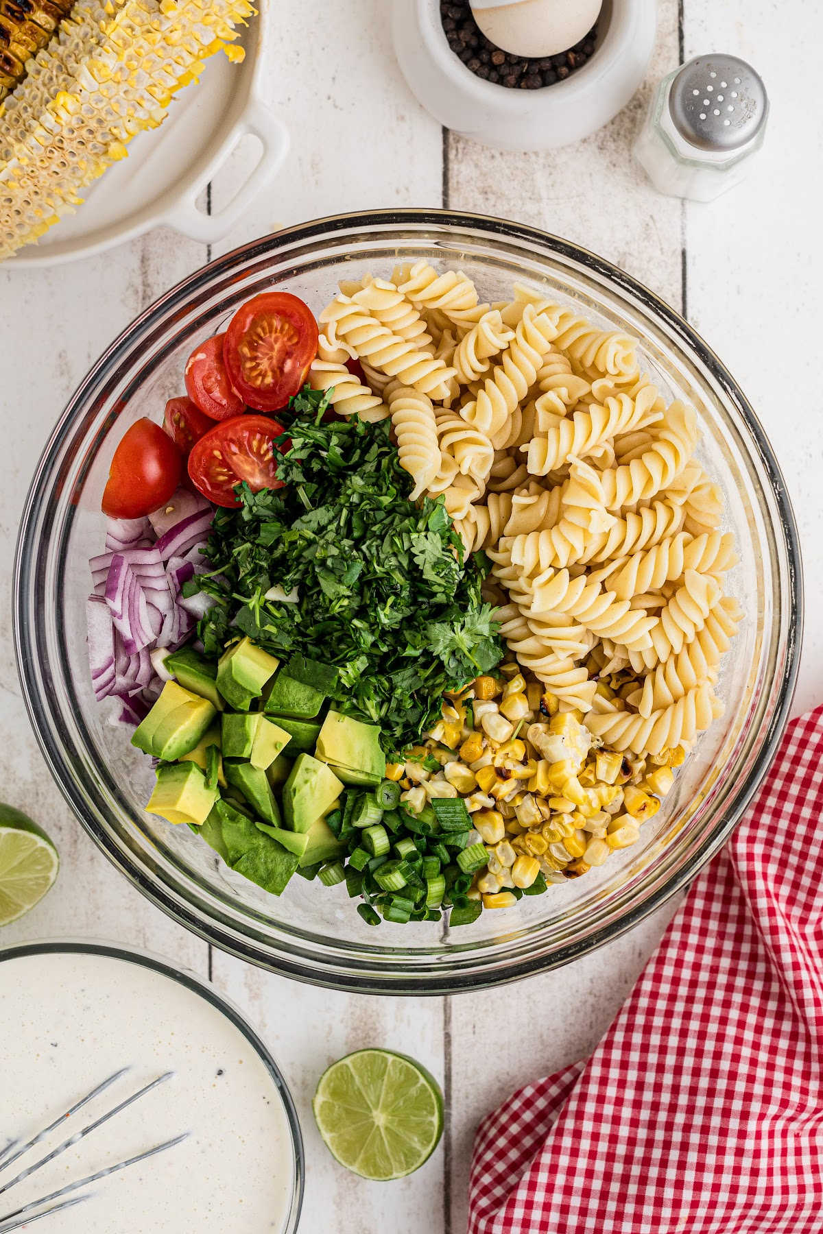A large mixing bowl with salad ingredients and pasta.