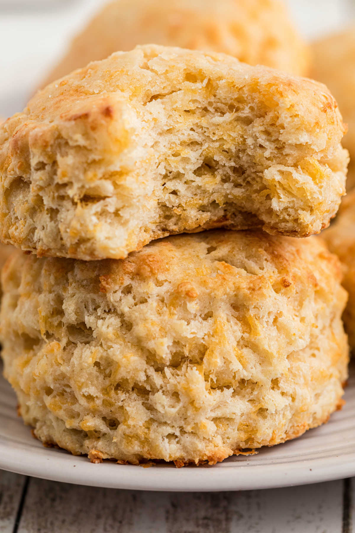 Close up of two cheesy biscuits, one with a bite taken out of it.