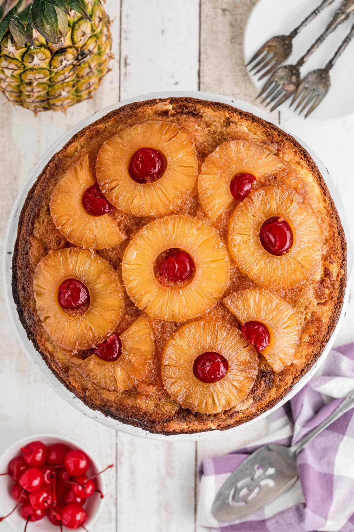 Overhead shot of a pineapple upside down cake, with slices of pineapples and cherries on top.