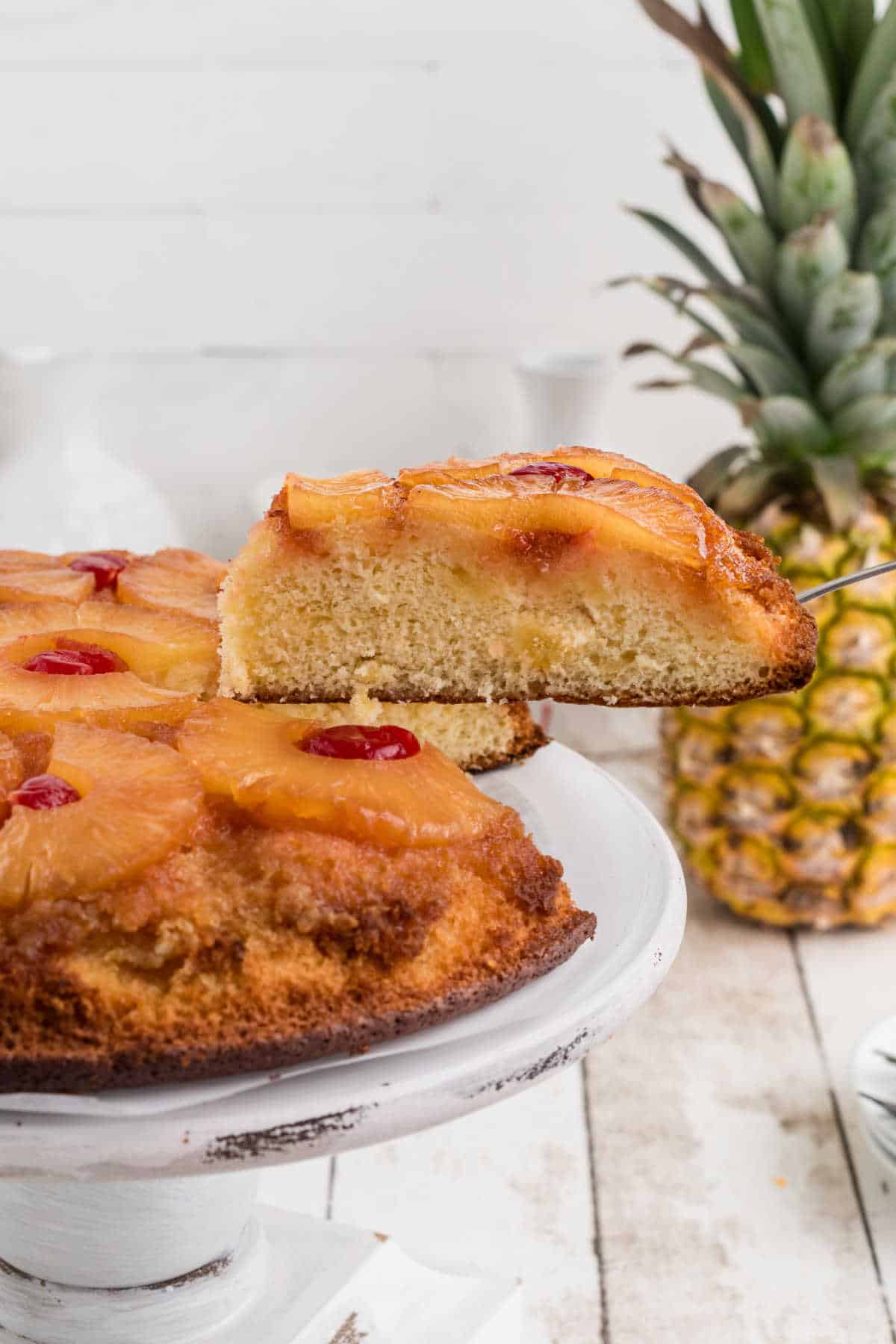 A slice of pineapple upside down cake being lifted out of the cake.