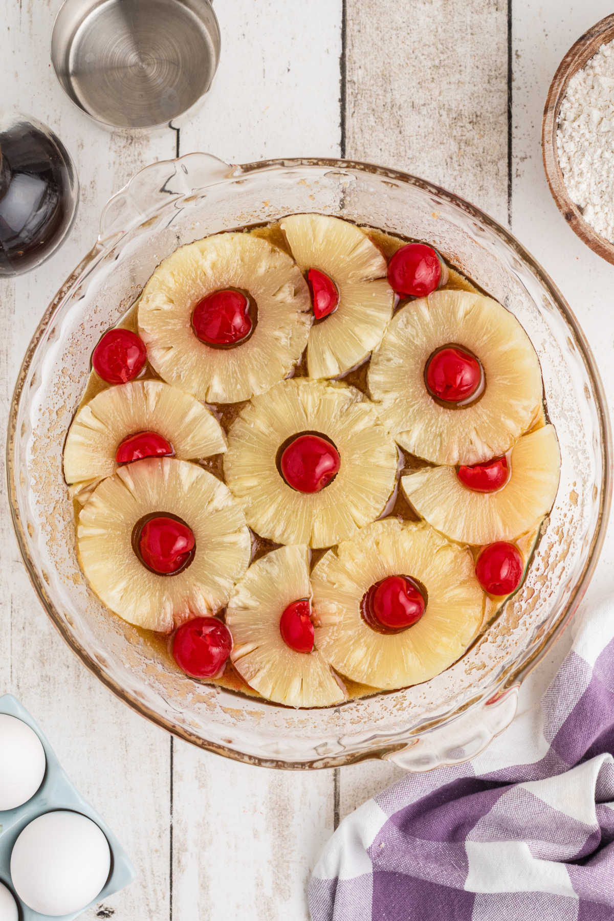 Cherries and pineapple slices arranged in a pie dish.