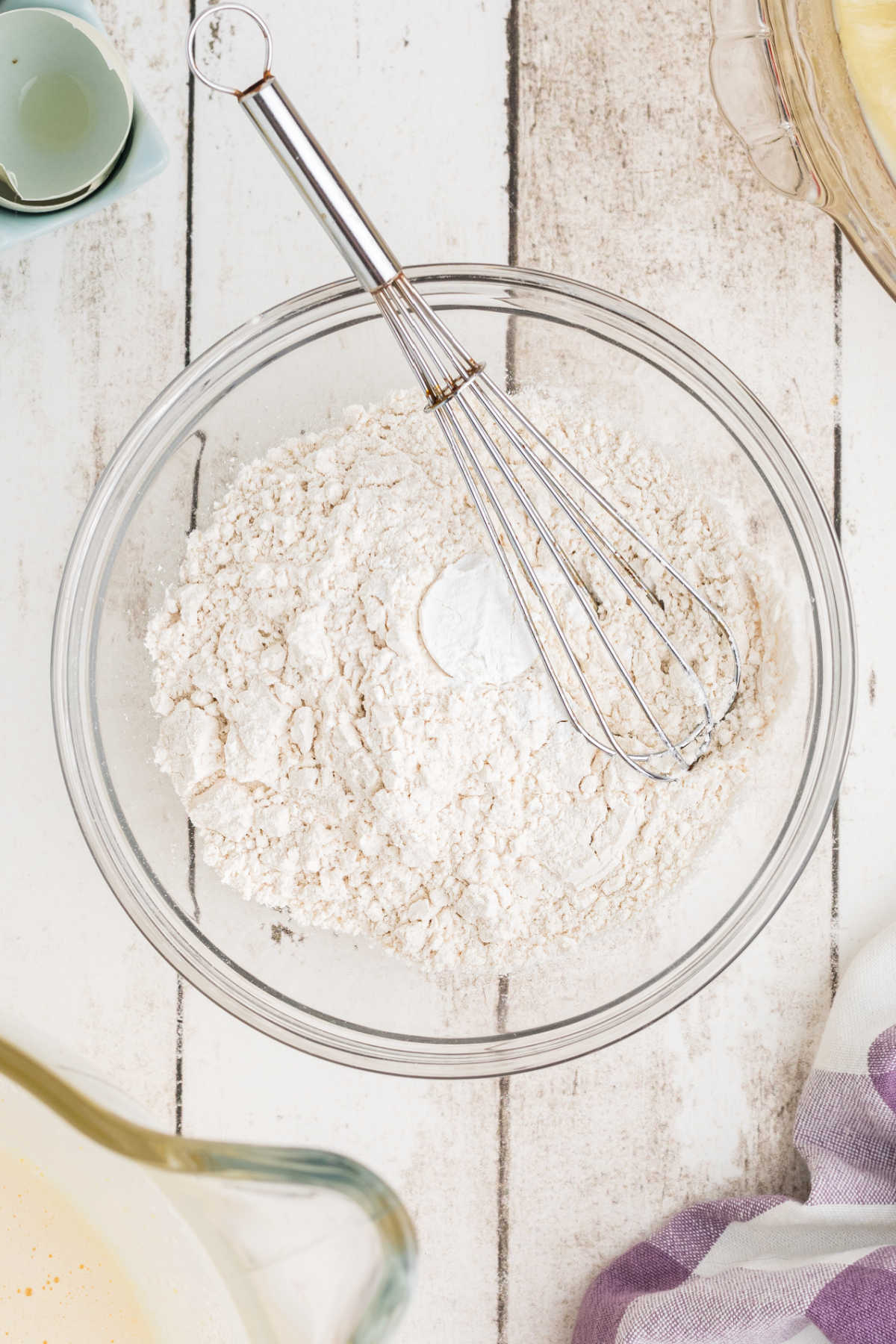 A large mixing bowl with flour and baking powder being mixed.