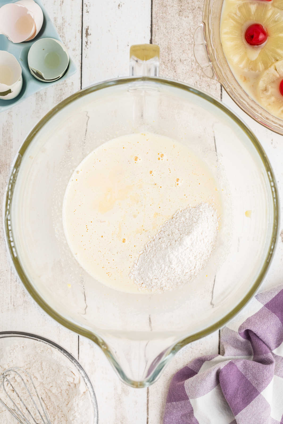 Dry mixture being added to a wet mixture in a mixing bowl.