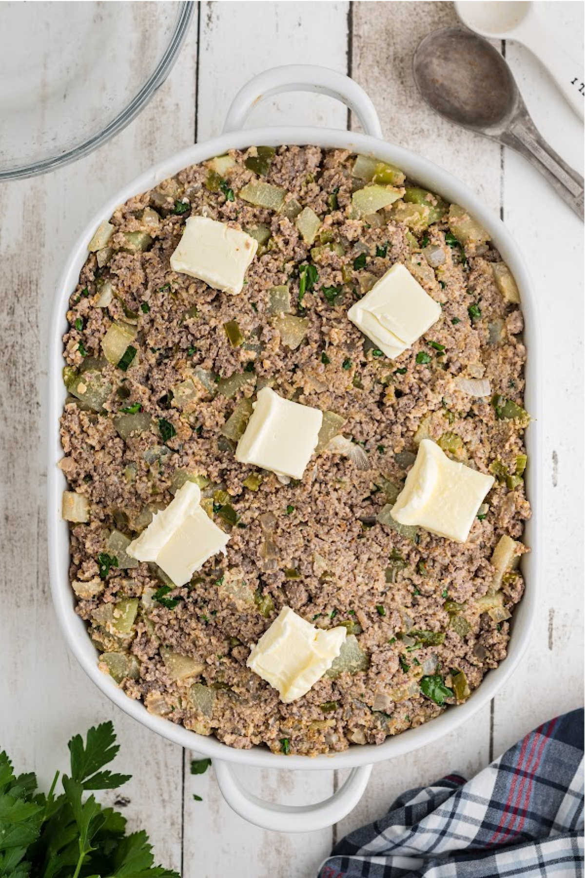 A baking dish filled with Mirliton dressing, with pats of butter on top.