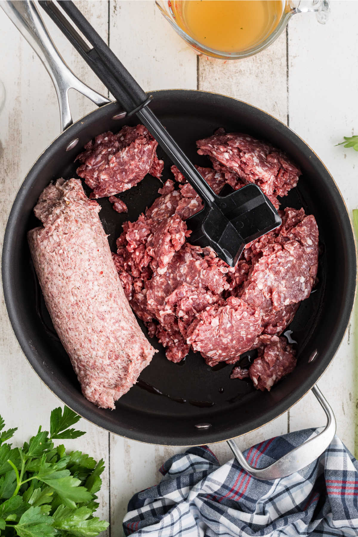 Ground meat and sausage added to a skillet to brown.