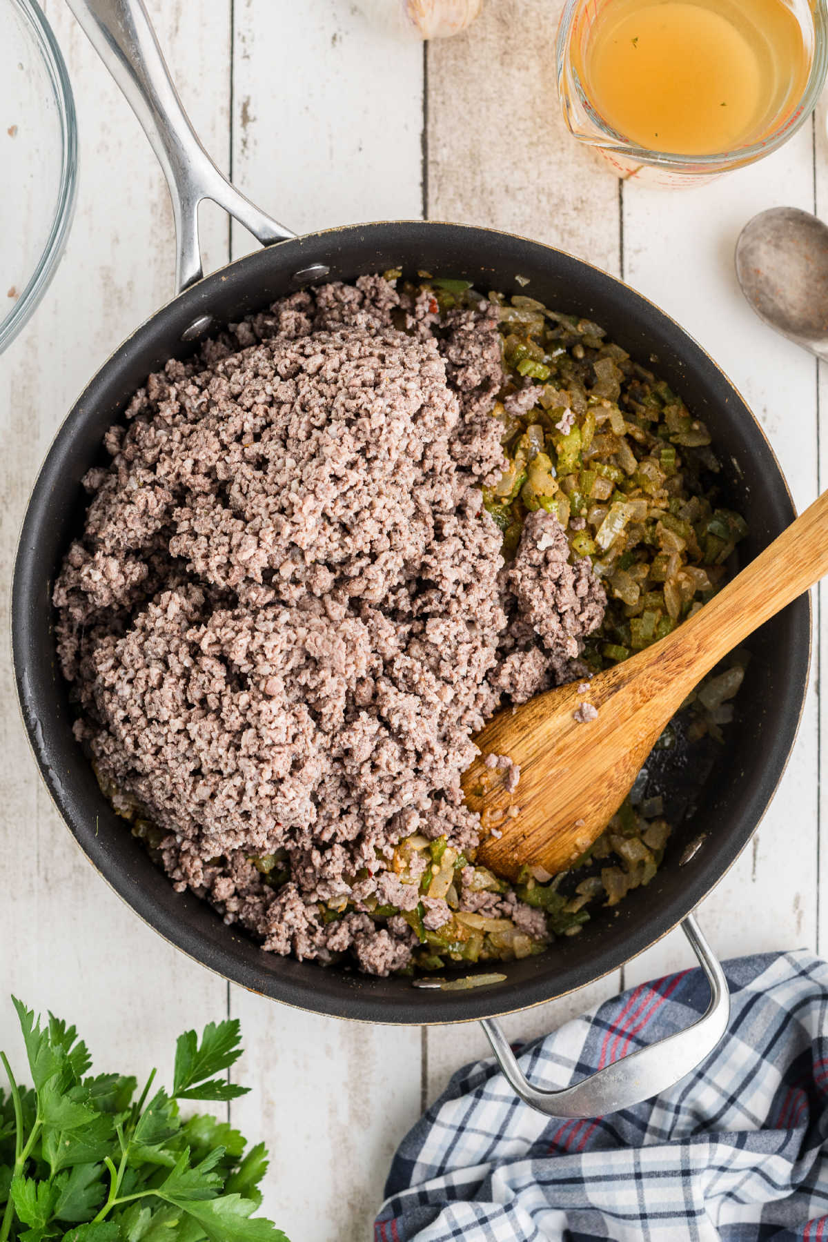 Ground meat added to a skillet full of veggies.