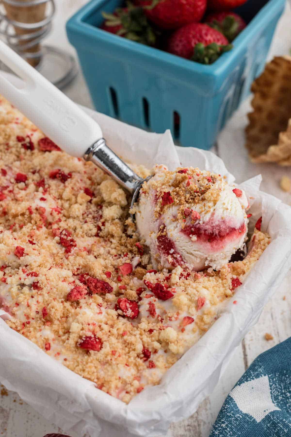 Picture of a loaf pan filled with strawberry shortcake ice cream with a scoop taking some out.