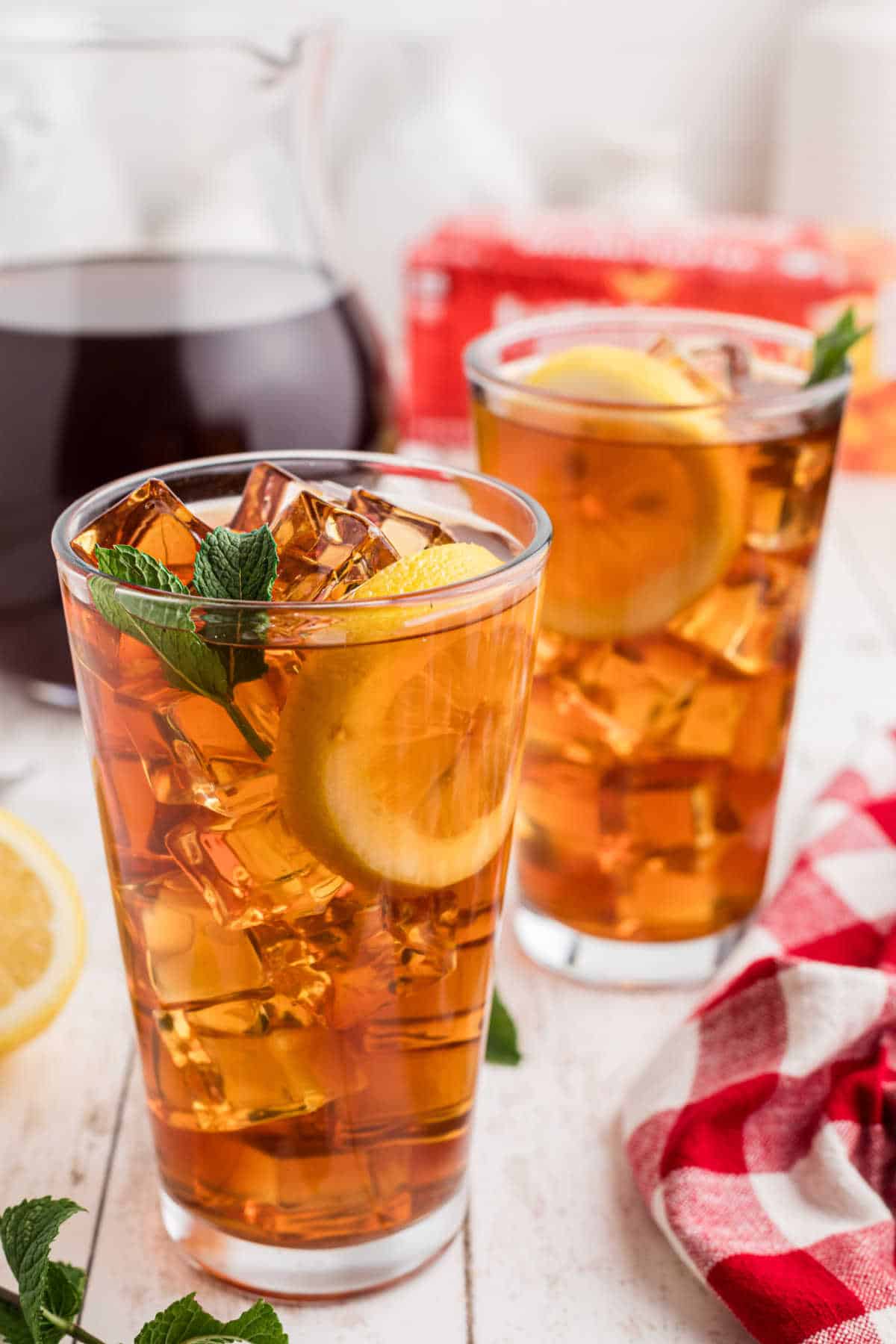 Tall glasses of sweet tea on ice with lemon and mint.