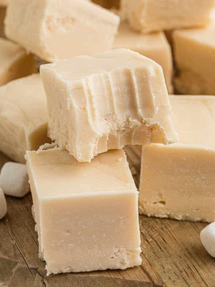 A pile of vanilla fudge with one having a bite taken out.