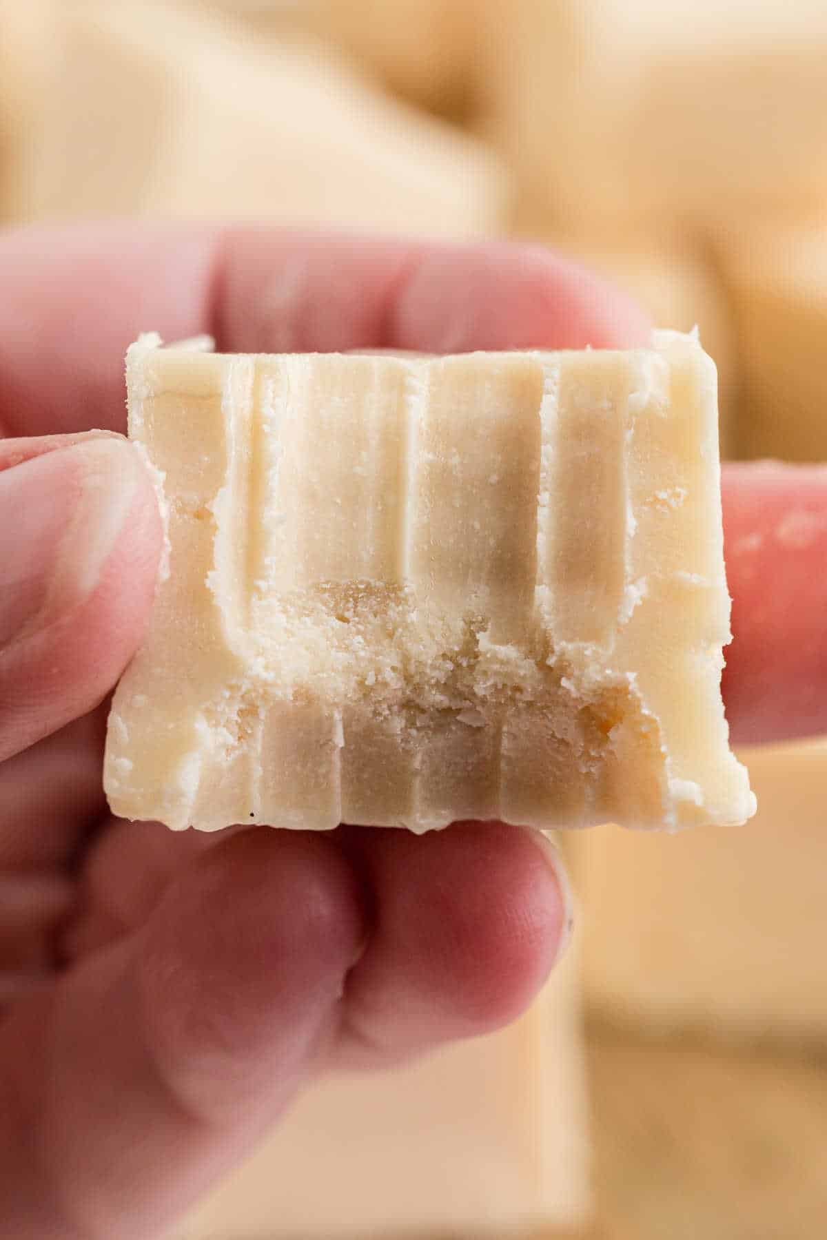 Close up of a piece of vanilla fudge with a bite taken out.