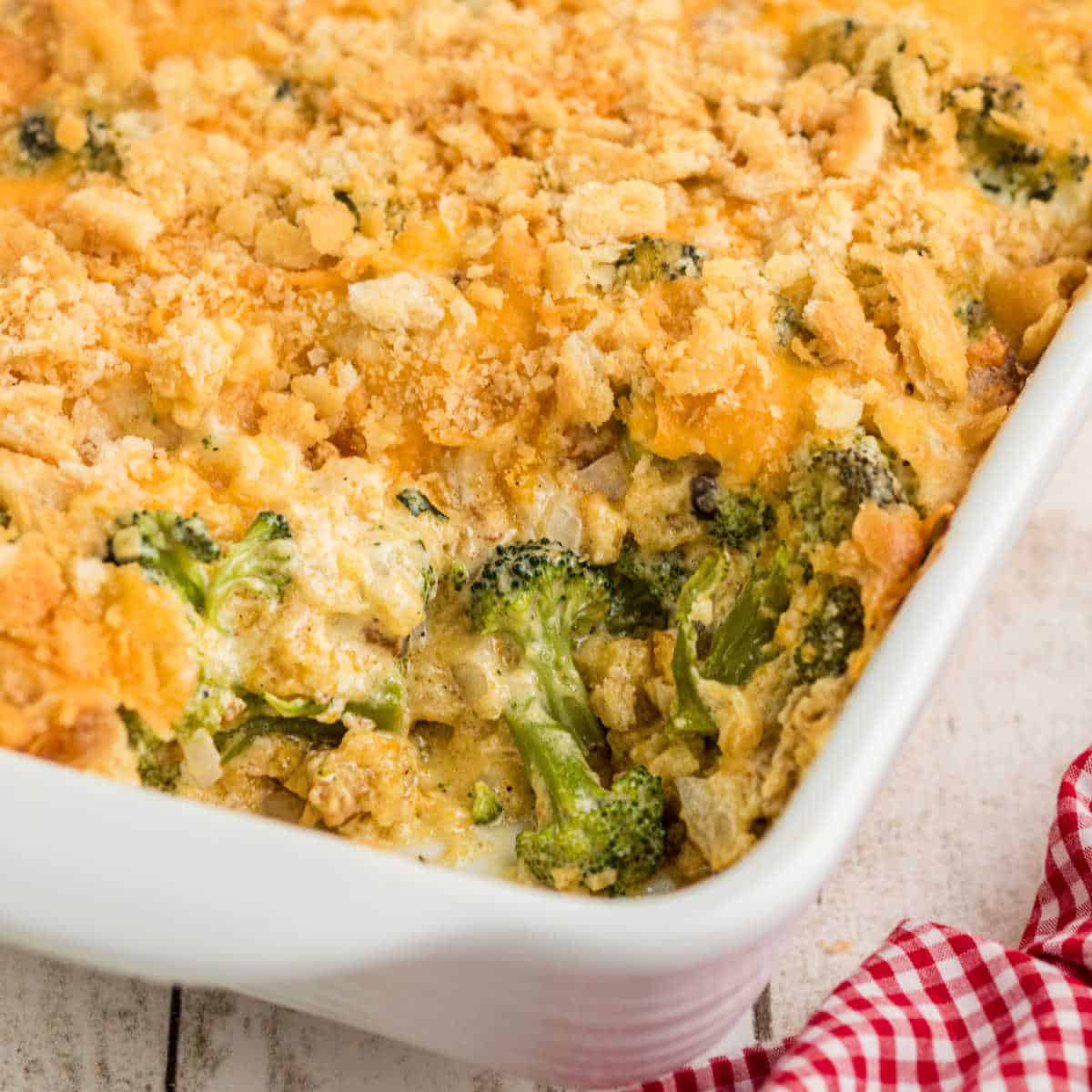 Close up of a corner of a baking dish with broccoli casserole, with a scoop missing.