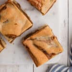 Overhead close up view of some caramel swirl blondies on a board.