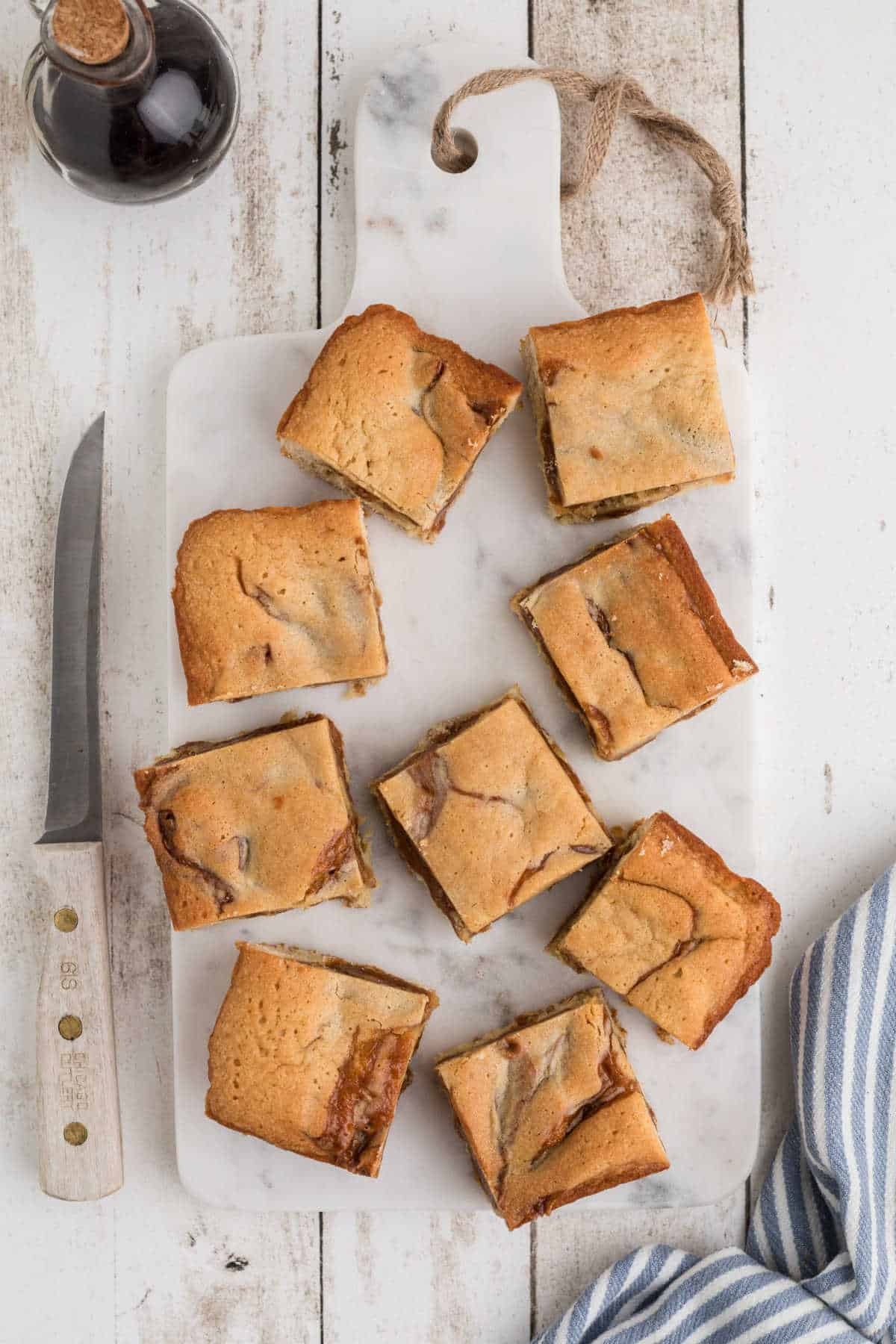 Overhead view of some caramel swirl blondies on a granite board.