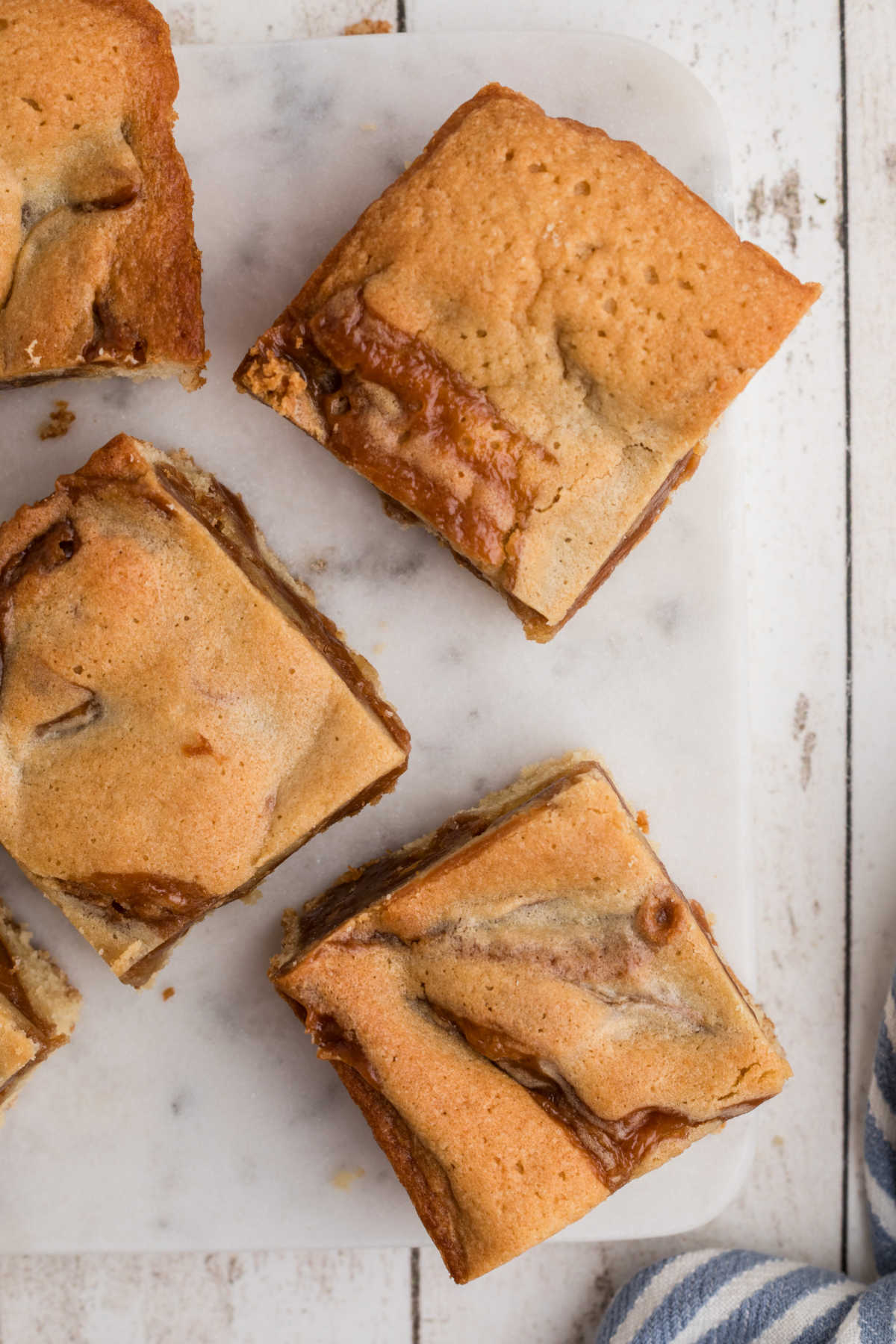 Overhead closeup of some caramel blondies on a granite plate.