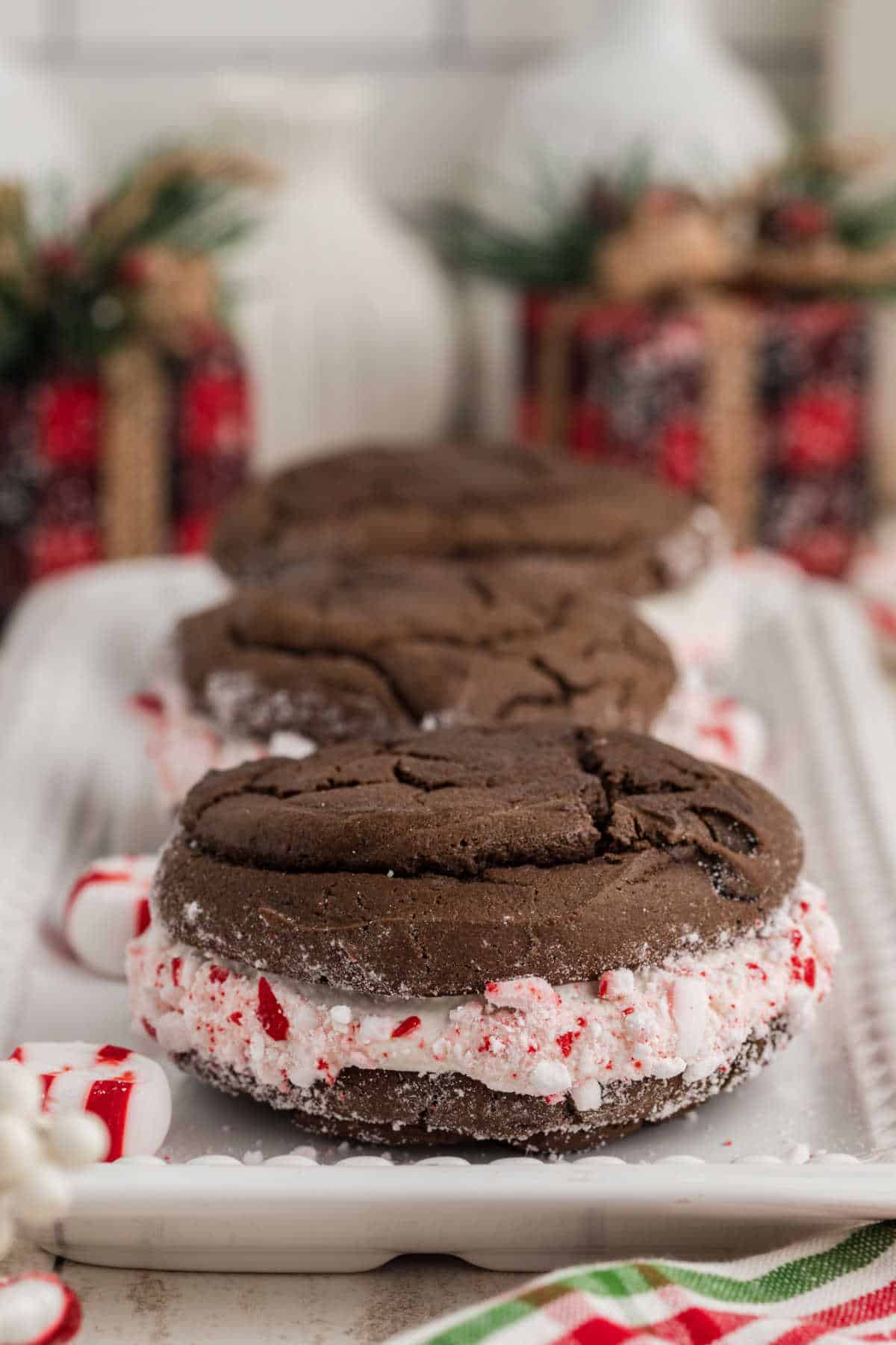 A straight on side image of some Christmas Whoopie Pies with some Christmas decorations in the background.