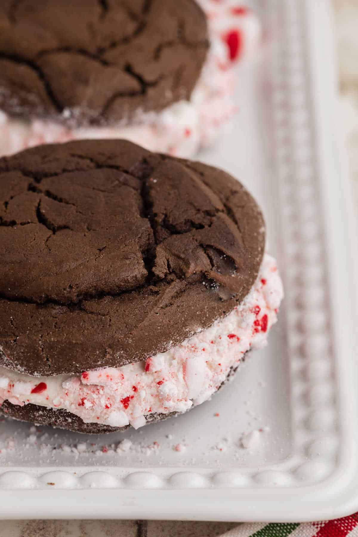 A close up side shot of some Christmas Whoopie Pies with crumbled peppermint candy.