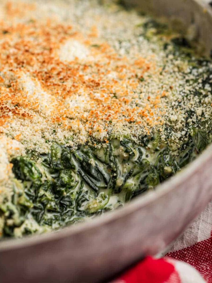 Close up shot of a spinach madeleine dish in a pan with a scoop missing.