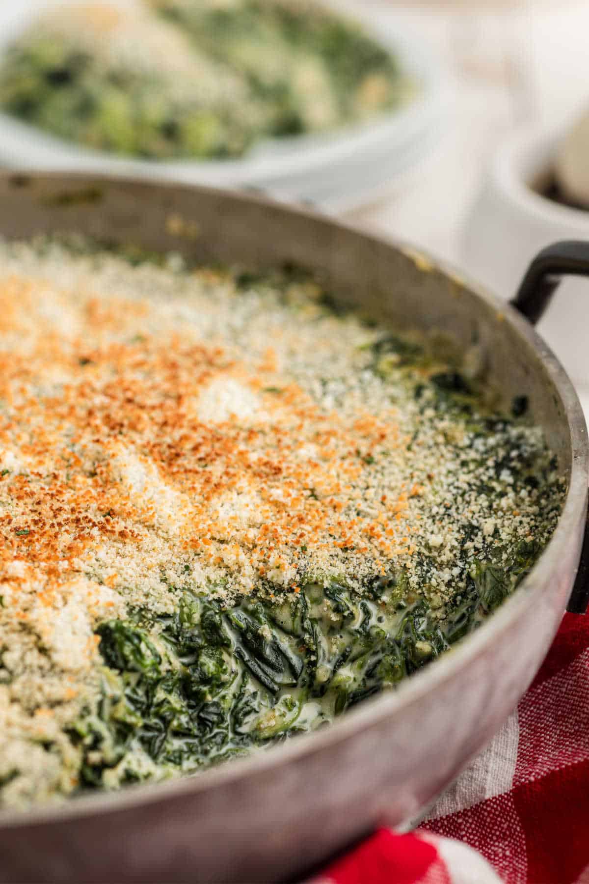 Side shot of a pan of spinach madeleine with a scoop missing.