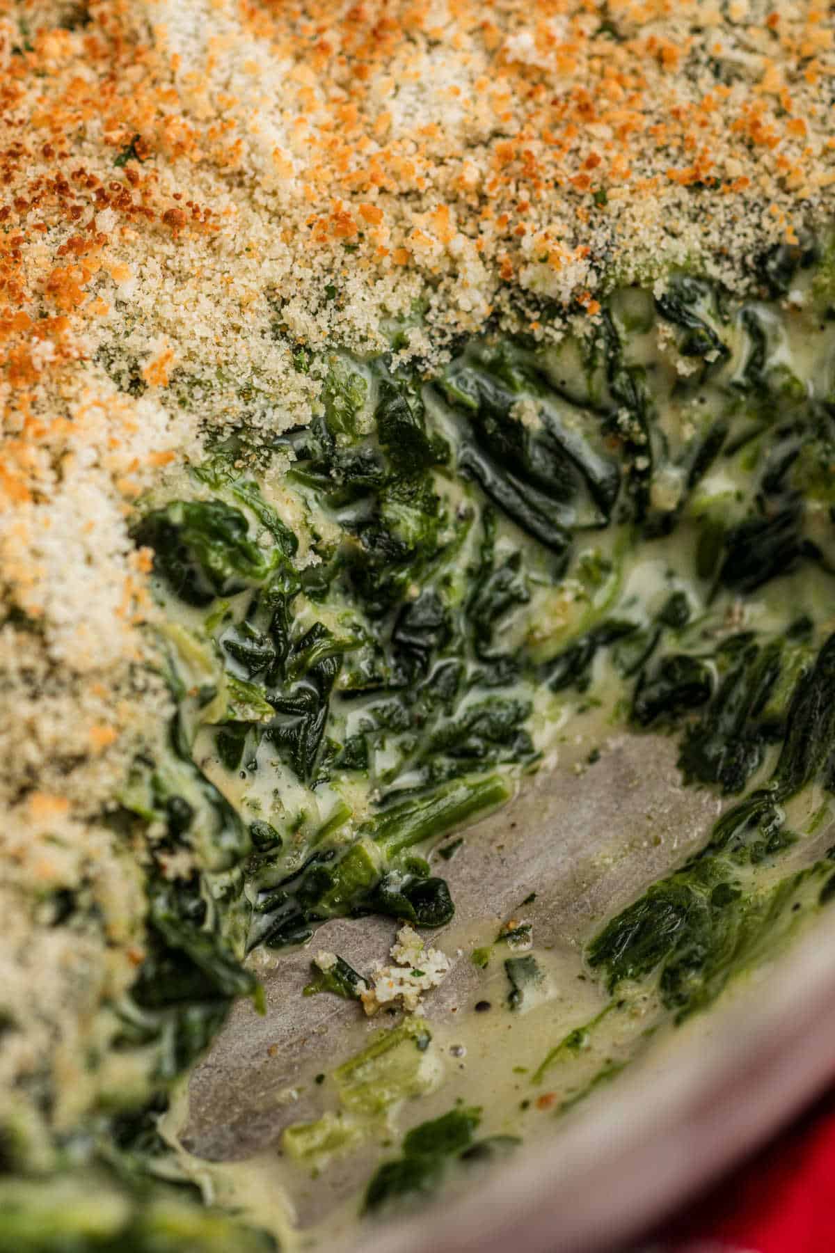 Very close up shot of a spinach madeleine dish, looking very cheesy and creamy.