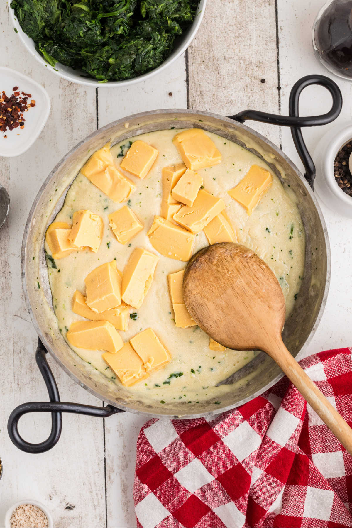 Cubed Velveeta cheese being added to a skillet with a roux cooking.