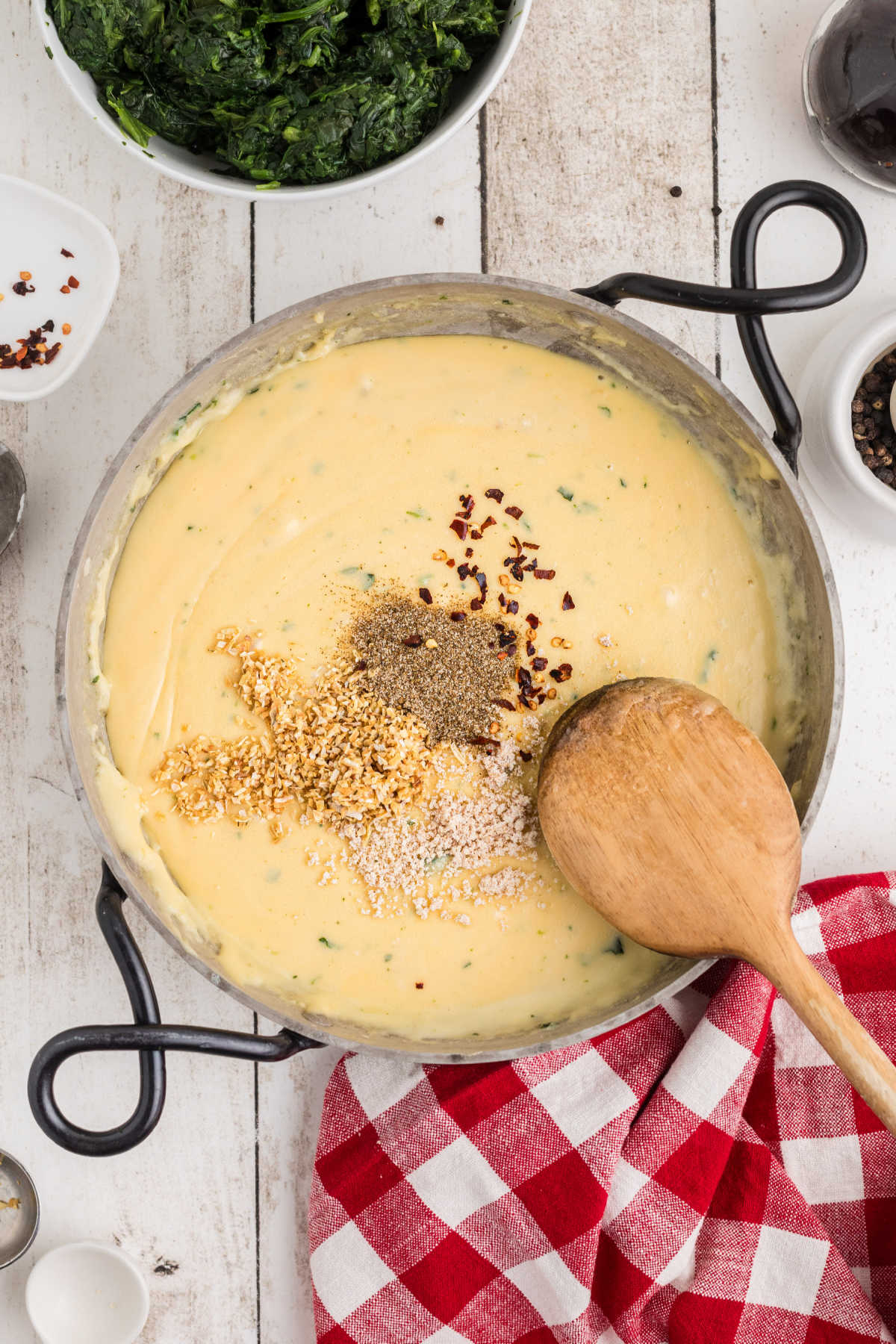 Seasonings added to a skillet with cheese sauce.