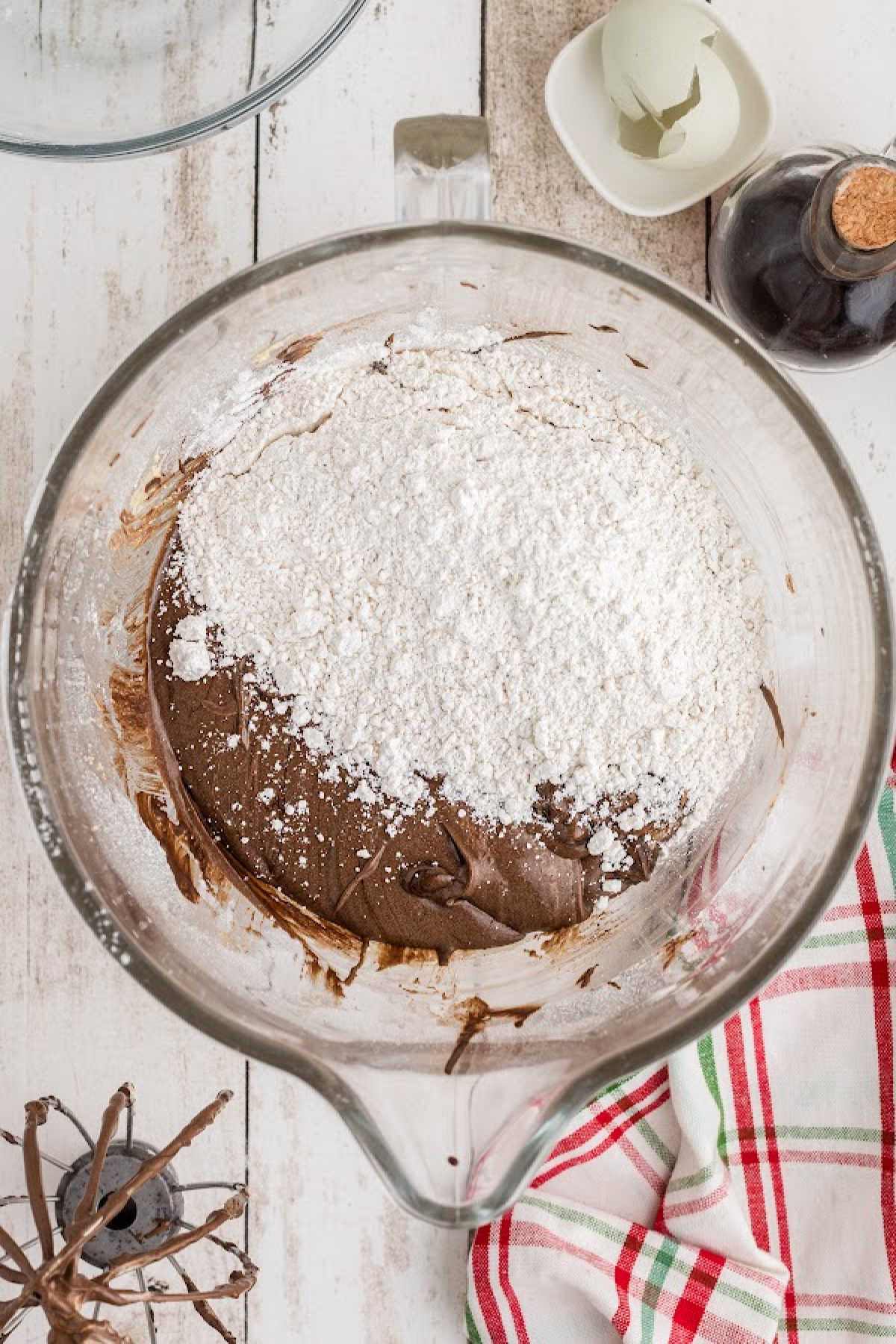 A flour mixture being added to a mixing bowl with a chocolate mixture.