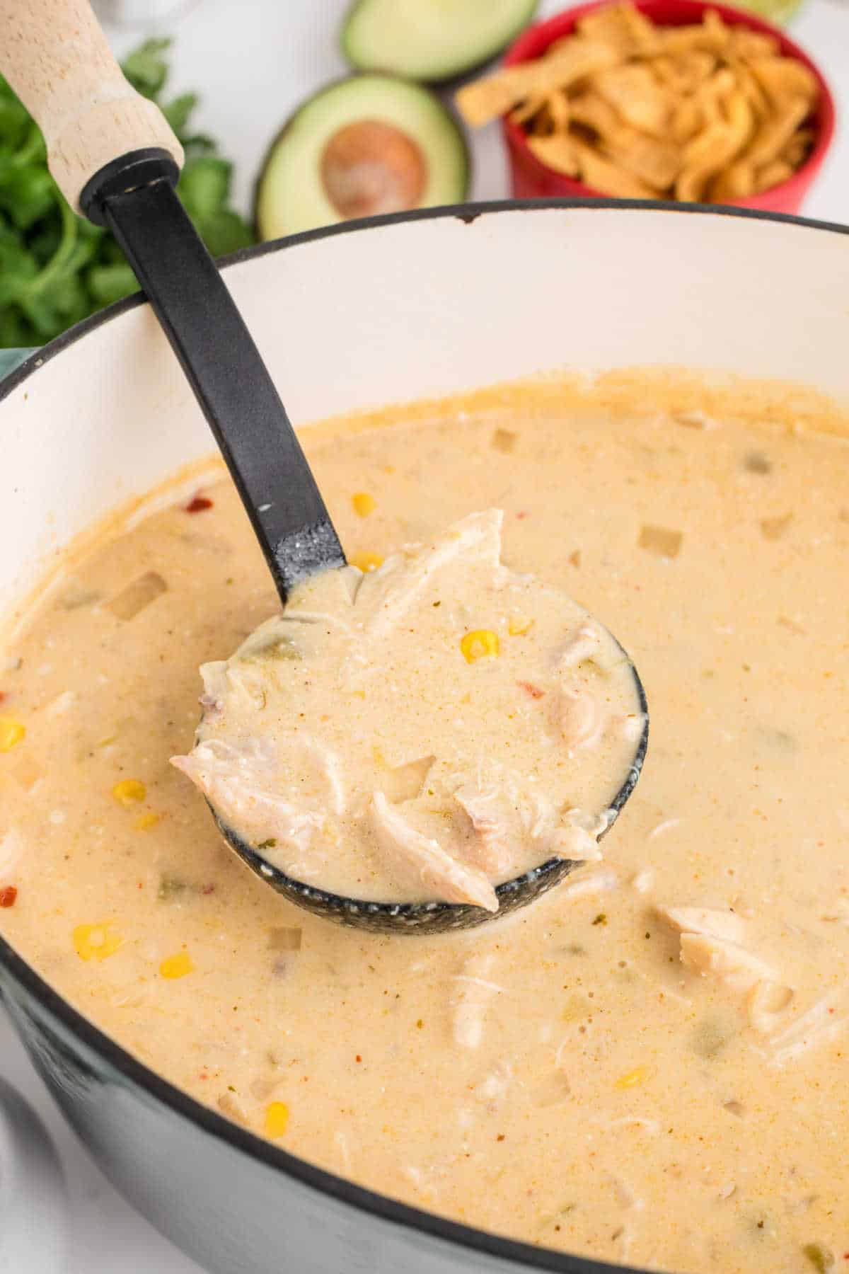 A large pot of white chicken chili with a ladle scooping some out.