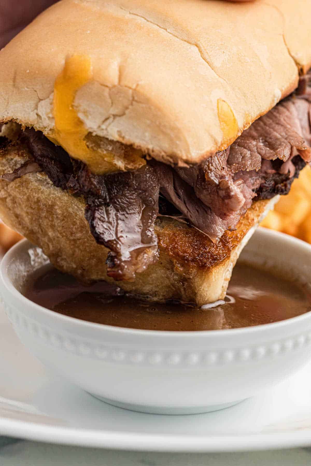 Leftover prime rib sandwich dipping into an au jus gravy.