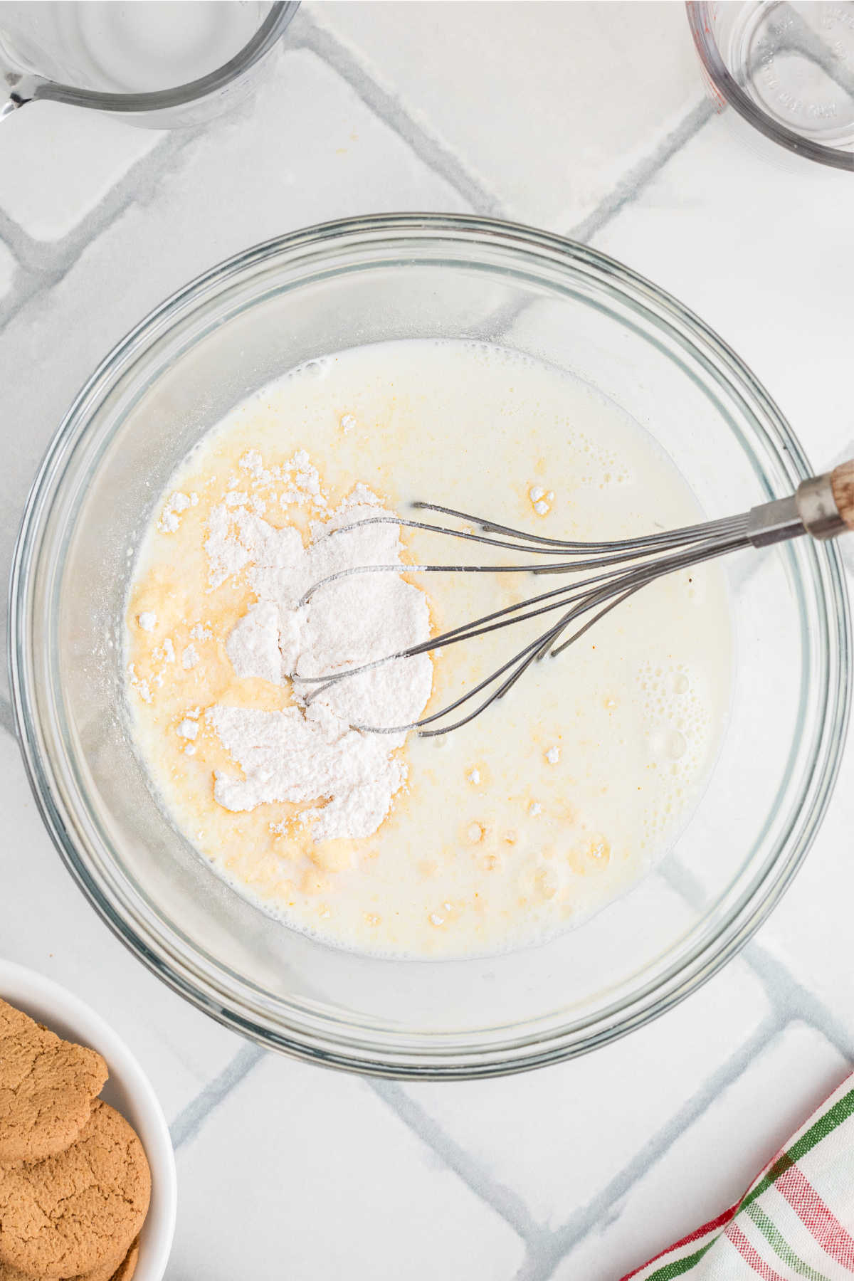 Pudding mix and milk in a glass mixing bowl about to be mixed.