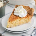 A slice of coconut pie with some cream squirted on top.