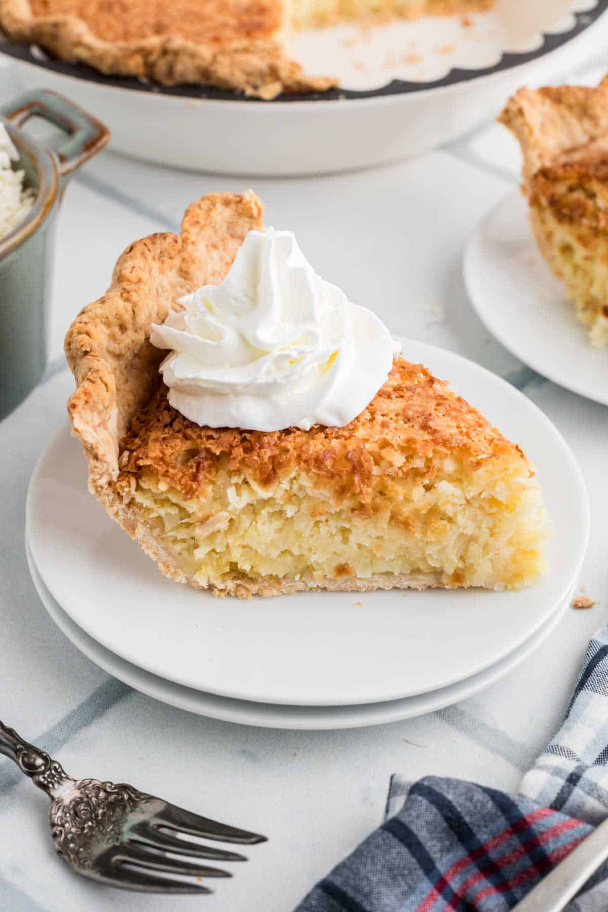 A slice of old fashioned coconut pie with some cream on top.