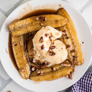Overhead shot of a plate of Bananas Foster with a dollop of ice cream in the middle.