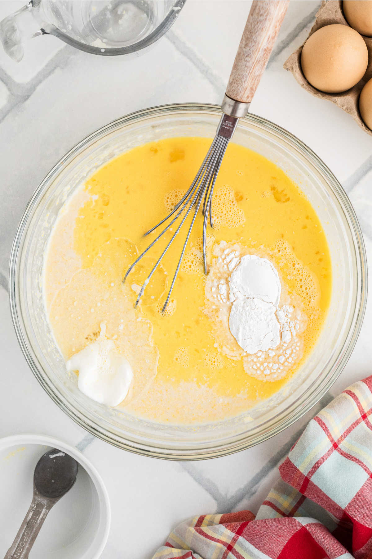 A large mixing bowl, filled with eggs, shortening and baking powder.