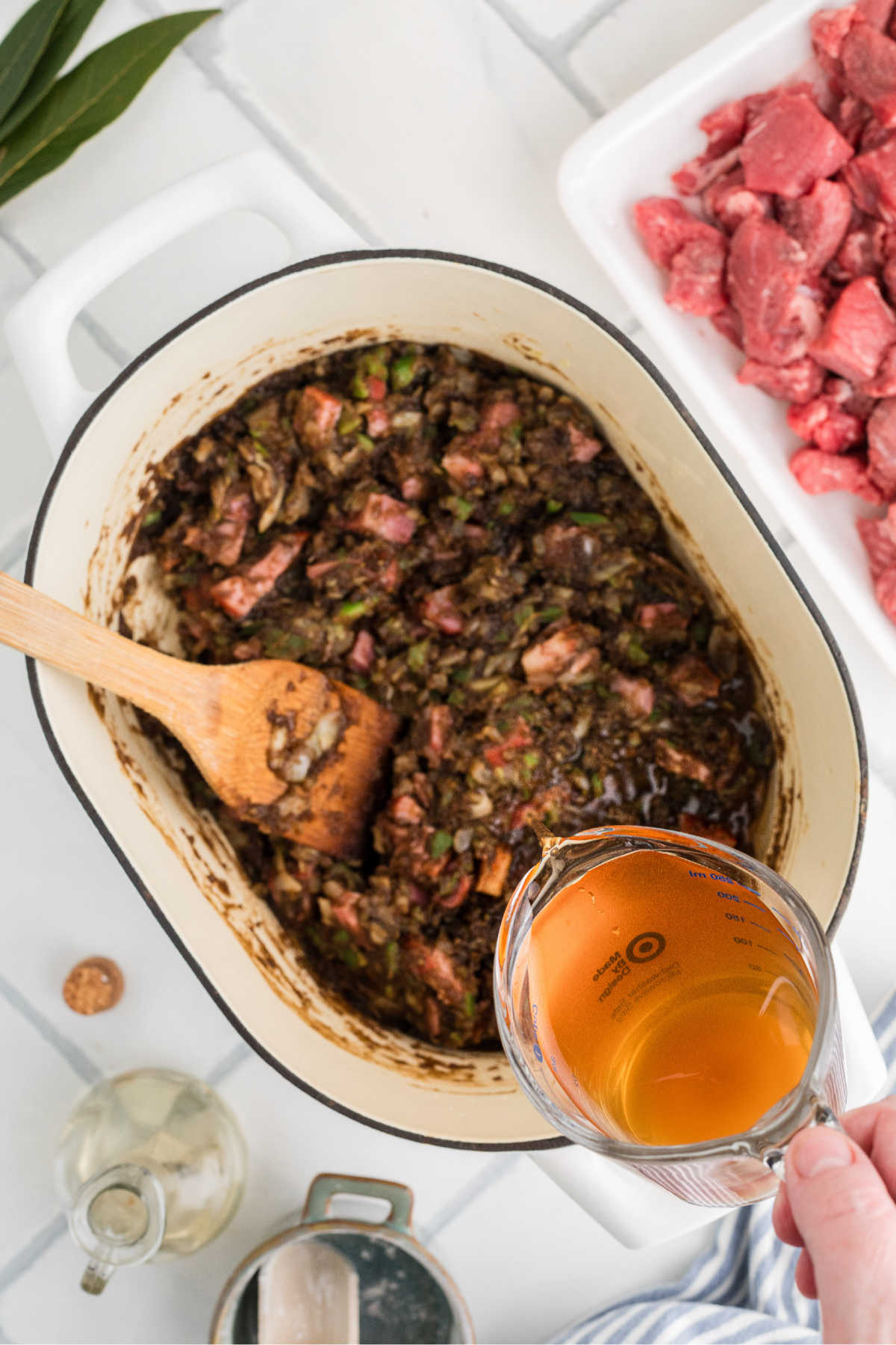 Beef broth being poured into a large pot with other ingredients.