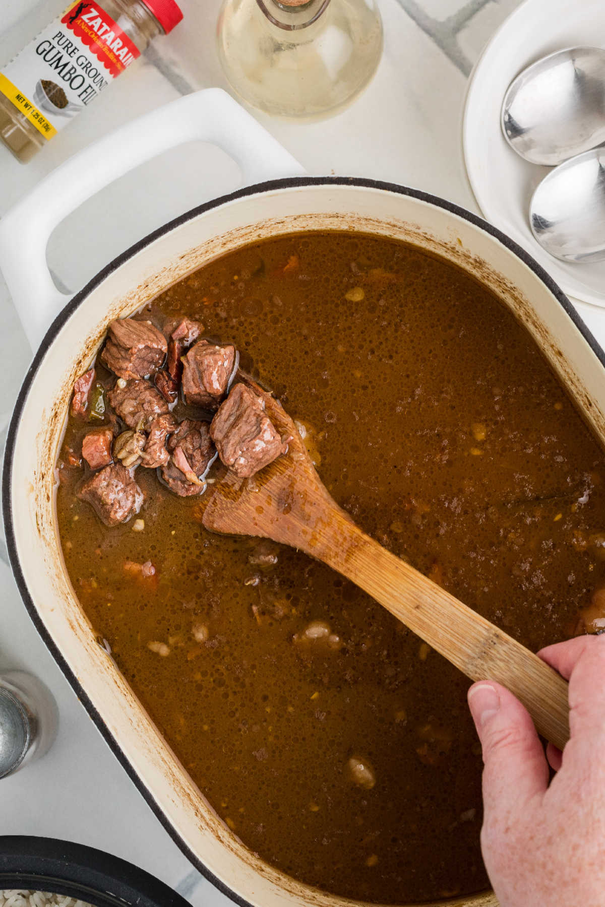 A large pot of beef gumbo slowly cooking.