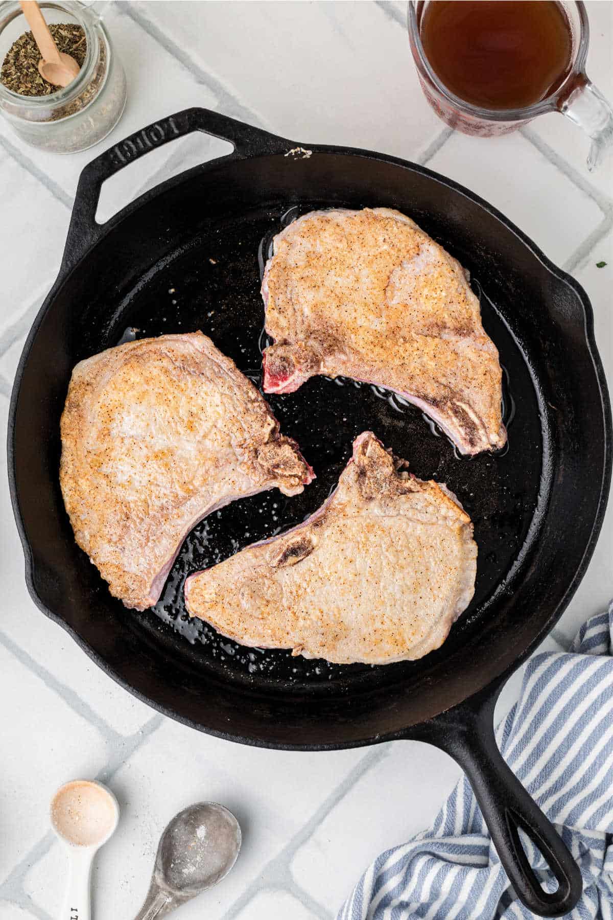 A cast iron skillet cooking some pork chops.