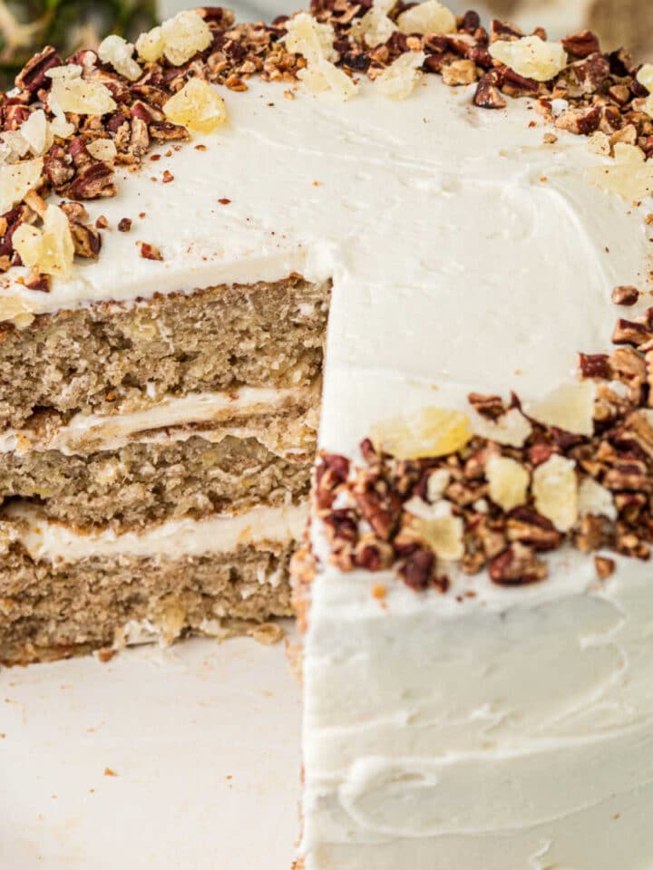An old fashioned hummingbird cake with some slices removed, the image is cropped square.