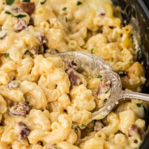 Close up of a spoon digging into a slow cooker cajun mac and cheese dish.