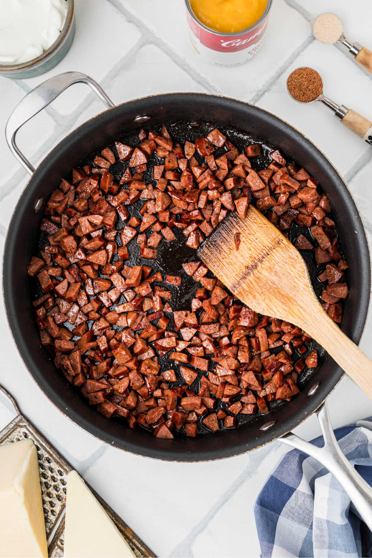 A large skillet with chopped andouille sausage.
