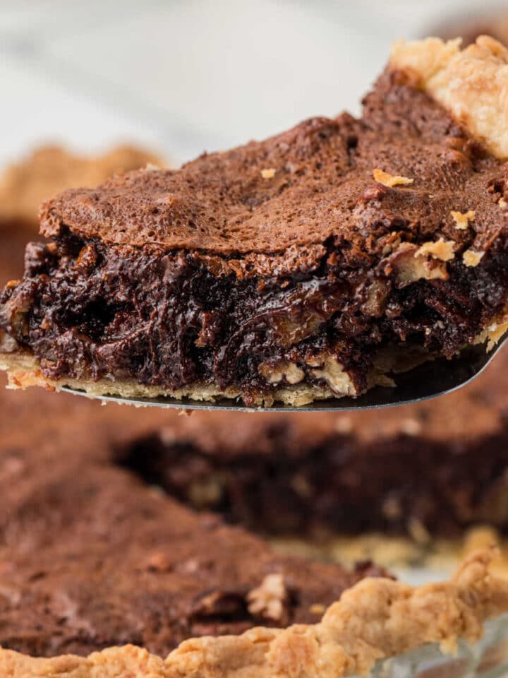 A slice of chocolate pecan pie being lifted out of the pie dish.