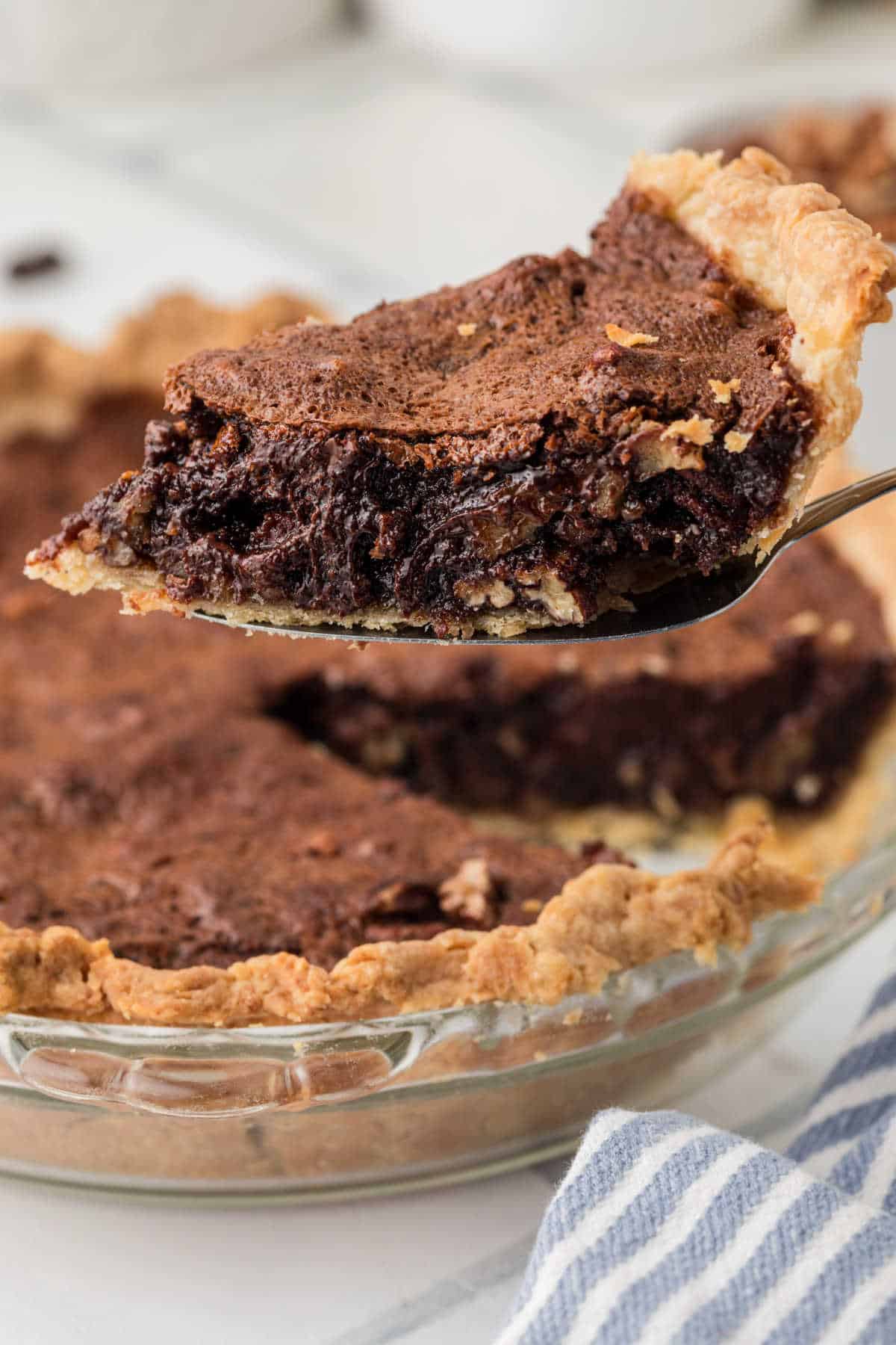 A slice of chocolate pecan pie being lifted out of a pie dish.