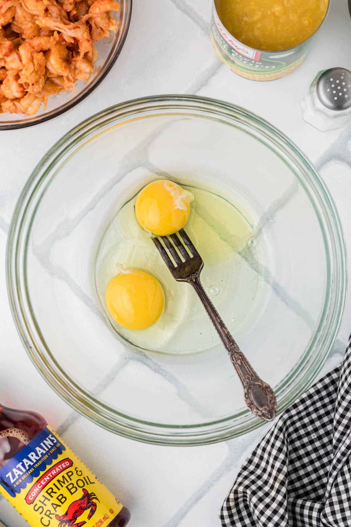 Two eggs cracked into a mixing bowl with a fork resting, about to mix.