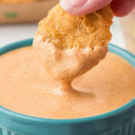 A McDonald's chicken nugget being dipped into a bowl of Cajun Sauce.