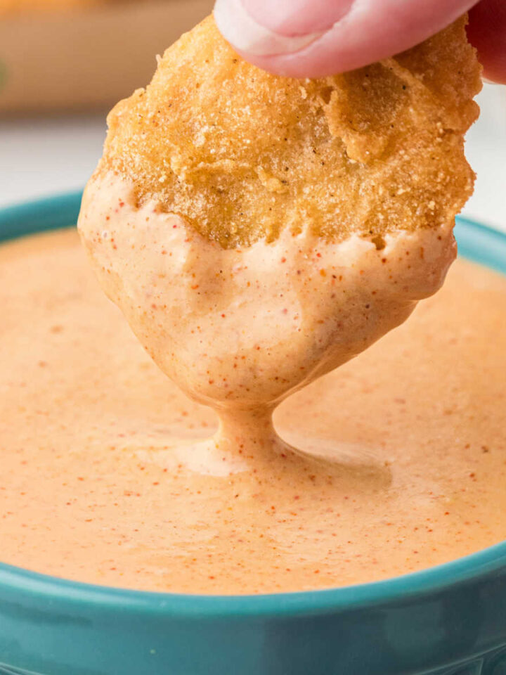 A McDonald's chicken nugget being dipped into a bowl of Cajun Sauce.