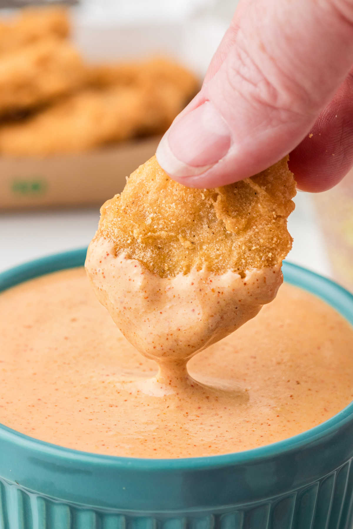 A McDonald's chicken nugget being dipped into a Cajun Sauce.