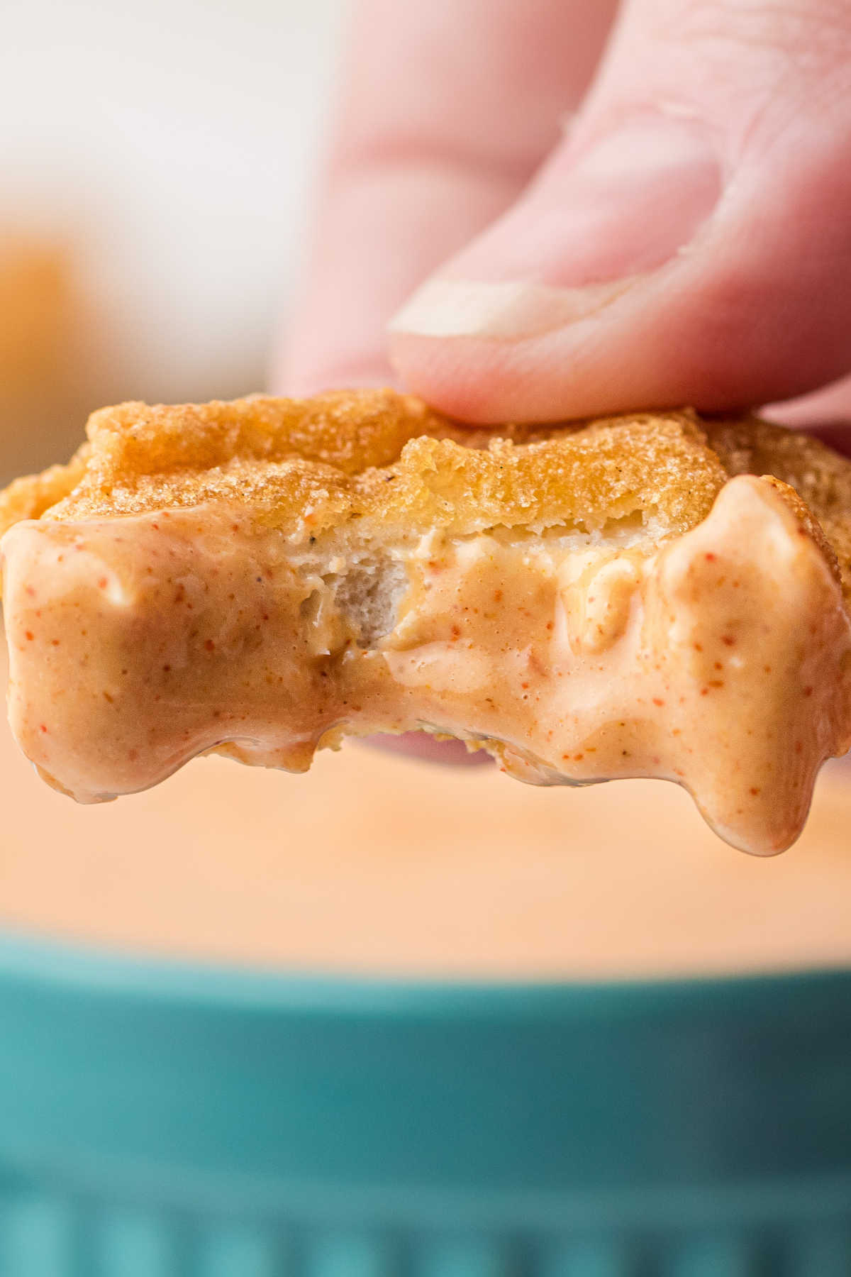 Close up of a chicken nugget that has been dipped in Cajun sauce.